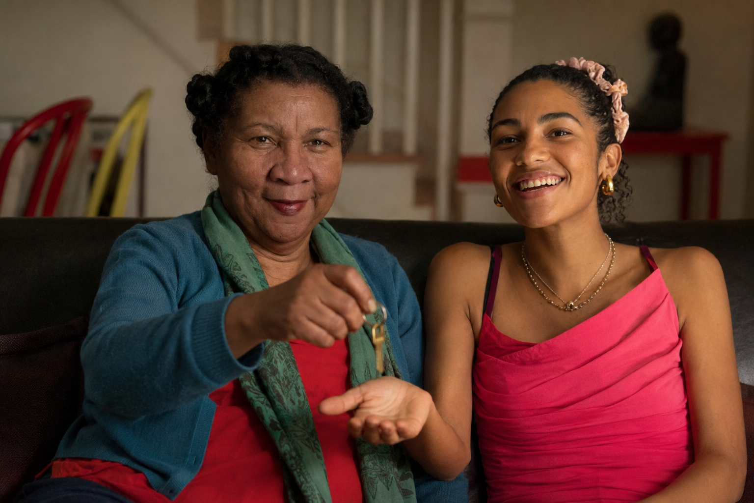 Older woman handing keys to a smiling woman in a pink dress